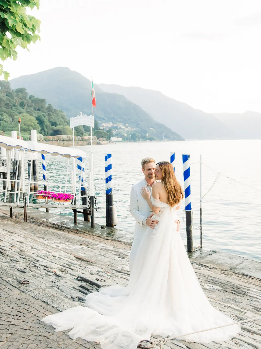 Romantic engagement moment on the shores of Lake Como, with the couple framed by the serene waters and distant mountains.