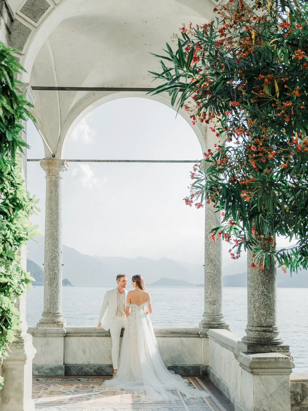Breathtaking Italian destination wedding at Lake Como, showcasing the bride's flowing gown and the groom's classic suit against the scenic landscape of Villa Monastero