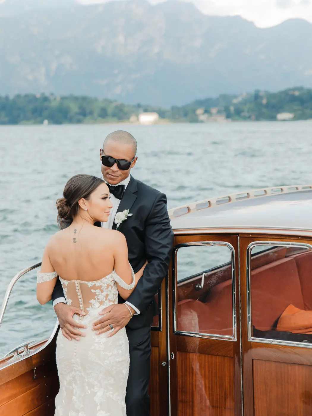 A candid moment captured as the newlyweds share hugs on a boat with the enchanting backdrop of Lake Como's azure waters
