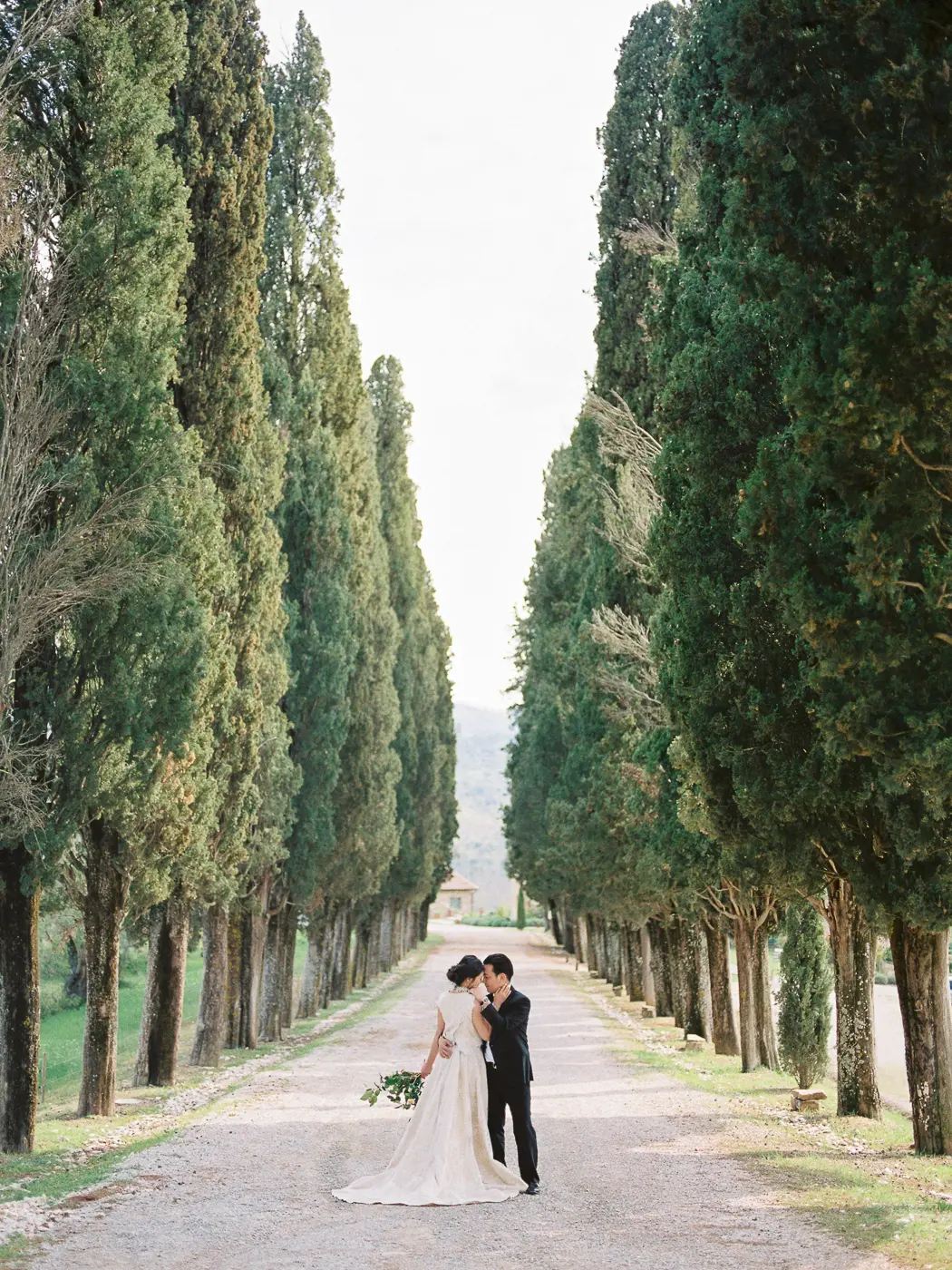 A panoramic view of the engaged couple against the picturesque scenery of Tuscany with iconic road with cypress trees